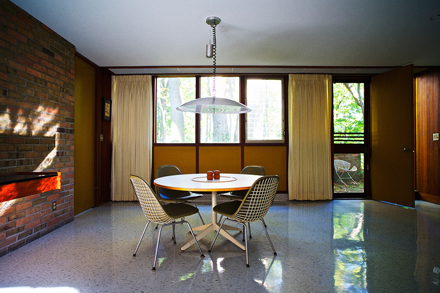 The dining area on the opposite side of the living room features upholstered Eames Wire Chairs and a Nelson Table—both  customized to a lower height. Corner recreated the pendant light based on original drawings and photographs.
